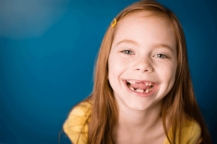 young girl smiling with her front teeth missing